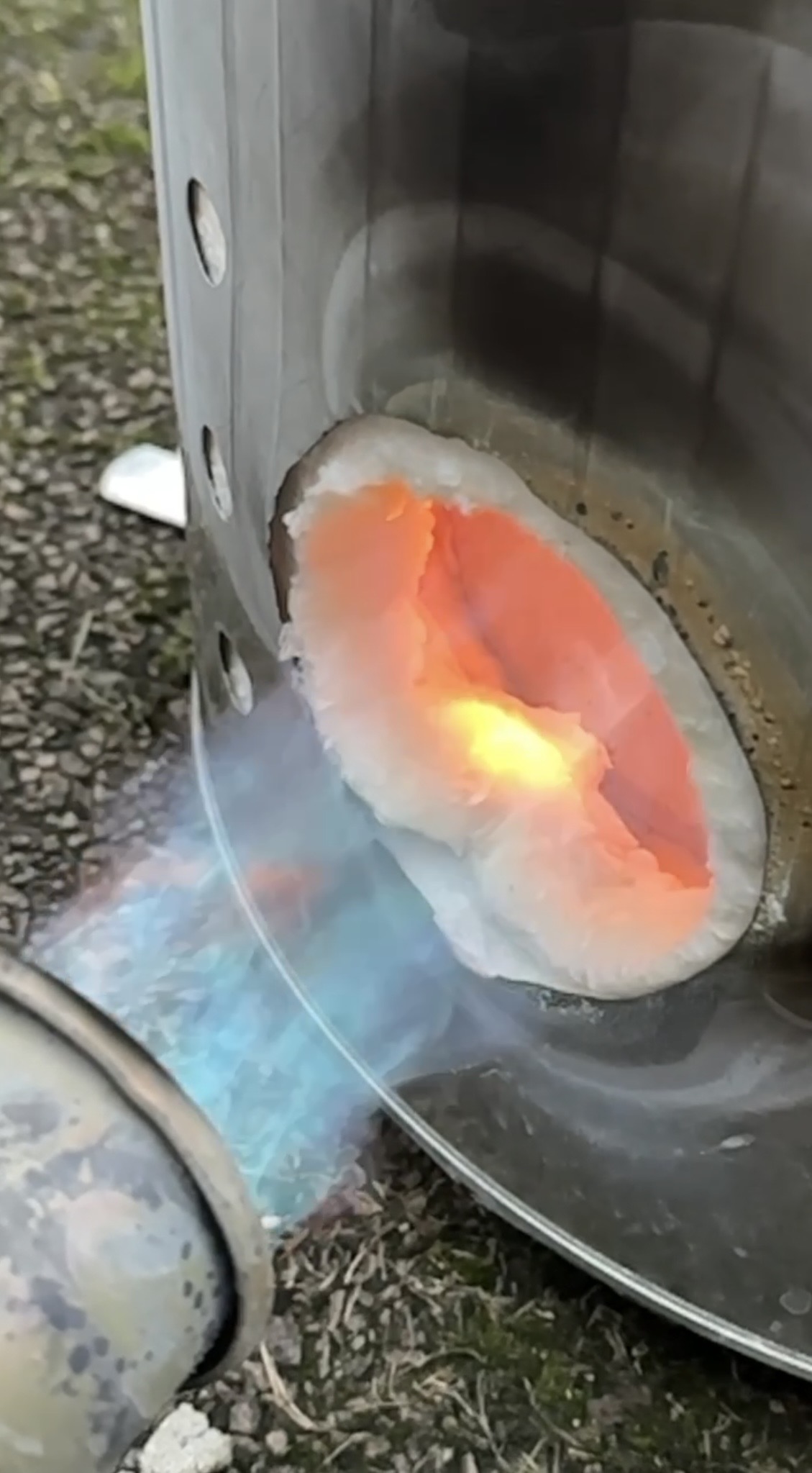 A ceramic piece glowing orange inside the open Raku kiln